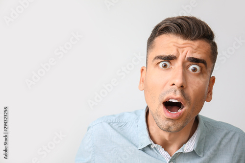 Shocked young man on light background