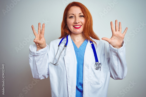 Young redhead doctor woman using stethoscope over white isolated background showing and pointing up with fingers number eight while smiling confident and happy.
