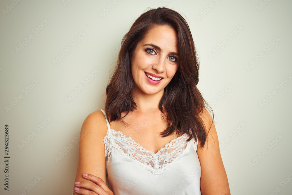 Young beautiful woman wearing t-shirt standing over white isolated background happy face smiling with crossed arms looking at the camera. Positive person. Young beautiful woman wearing t-shirt standing over white isolated background happy face smiling with crossed arms looking at the camera. Positive person.