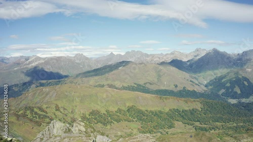 A young brave man standing on rocky cliff edge, looking away at beautiful natural landscape, mountain ranges and overgreen valleys. Aerial drone view of Caucasian Park. travel sport outdoor lifestyle photo