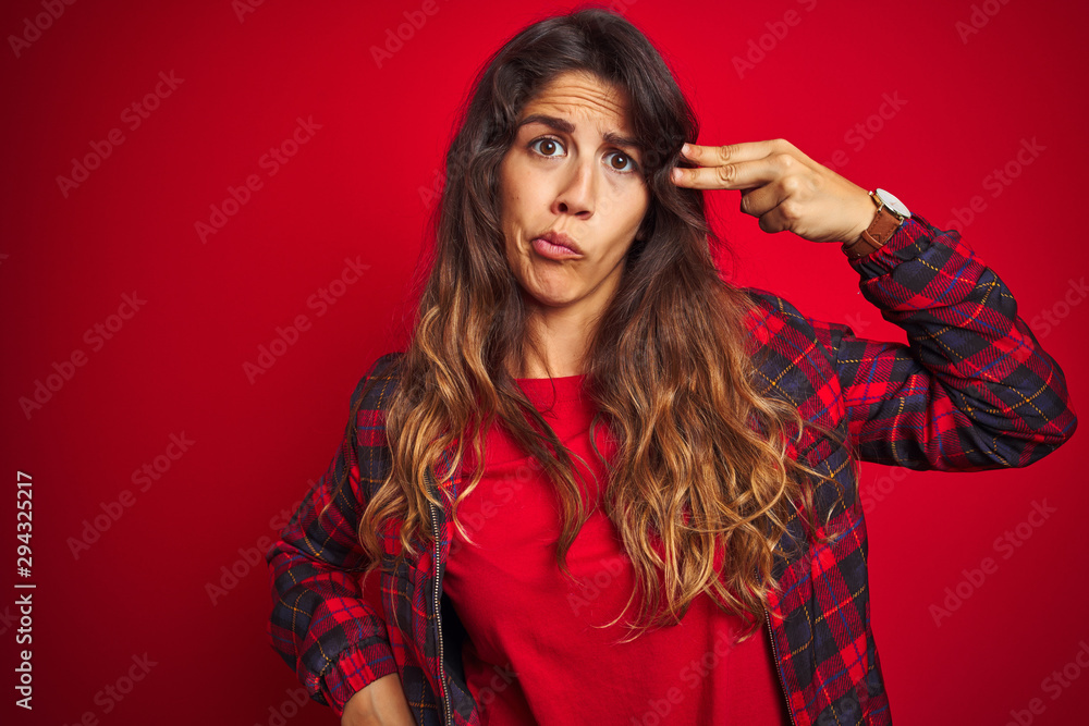 Young beautiful woman wearing casual jacket standing over red isolated background making fish face with lips, crazy and comical gesture. Funny expression. Young beautiful woman wearing casual jacket standing over red isolated background making fish face with lips, crazy and comical gesture. Funny expression.
