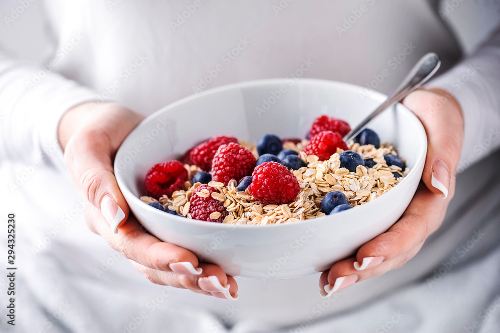 Oat flakes with forest fruits in white plate. Plate full of oat flakes and raspberries, blueberries in woman hands. Oat flakes with forest fruits in white plate. Plate full of oat flakes and raspberries, blueberries in woman hands.
