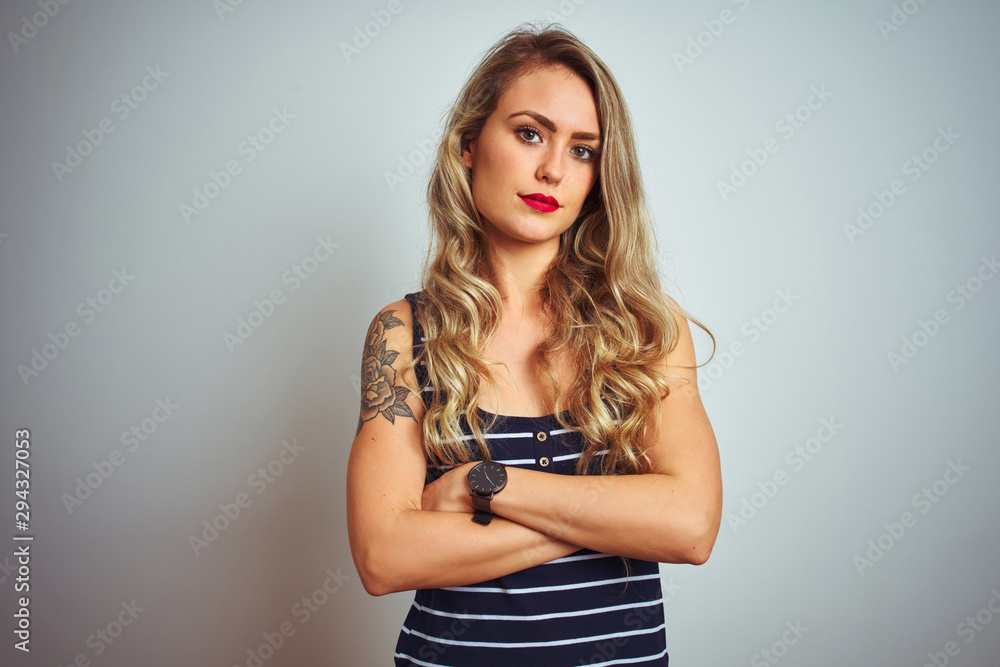 Young beautiful woman wearing stripes t-shirt standing over white isolated background skeptic and nervous, disapproving expression on face with crossed arms. Negative person. Young beautiful woman wearing stripes t-shirt standing over white isolated background skeptic and nervous, disapproving expression on face with crossed arms. Negative person.