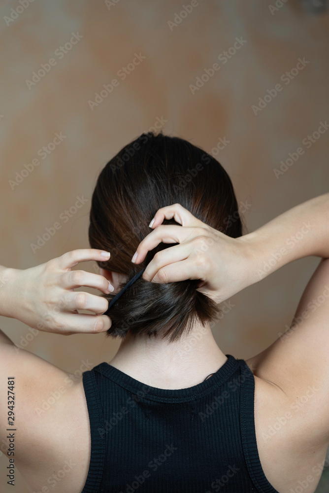 Naklejka premium Rear view of a lady arranging her hair