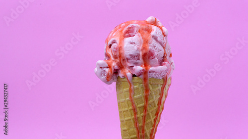 Strawberry ice cream scoop in waffle cone with  Strawberry sauce on pink background, Closeup Front view Food concept..