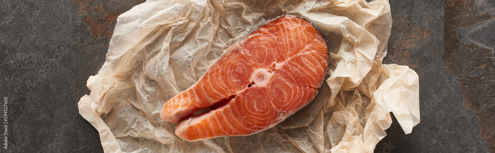 top view of raw salmon steak on bakery paper on stone table, panoramic shot