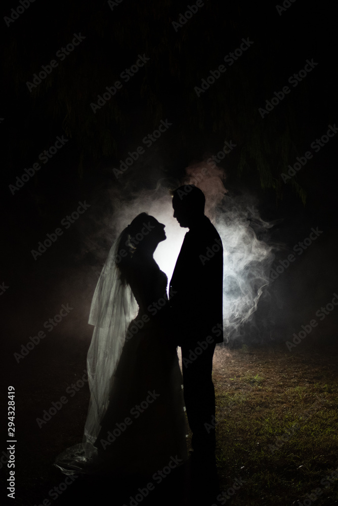 silhouette of a bride and groom at night with a smokey background