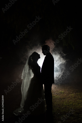 silhouette of a bride and groom at night with a smokey background