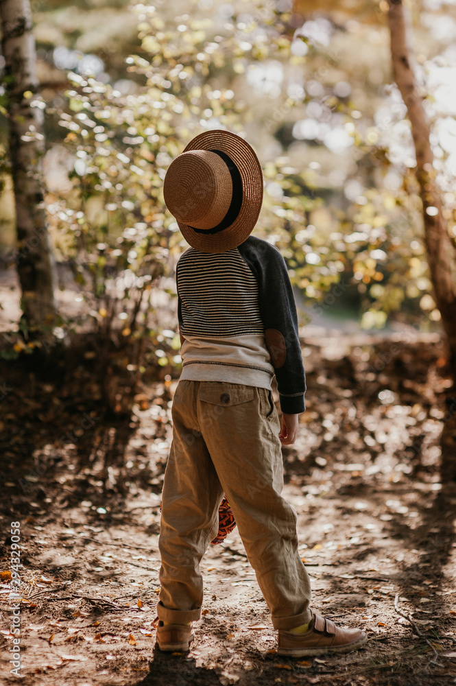 Stylish boy in a hat with a basket. boy in the park in a hat with a basket in autumn Stylish boy in a hat with a basket. boy in the park in a hat with a basket in autumn