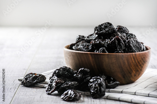 Prunes in wood bowl on white rustic table. Dried plums on white table. Fresh prunes for healthy life. photo