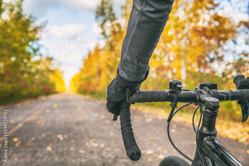 Biking first person view of bike cyclist POV showing hands and handlebar on road bicycle riding on outdoor commute in autumn nature.