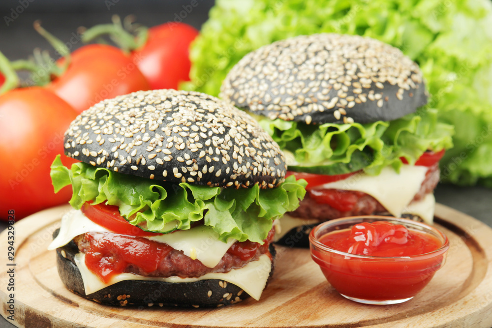 Two black burgers with vegetables and beef meat Two black burgers with vegetables and beef meat
