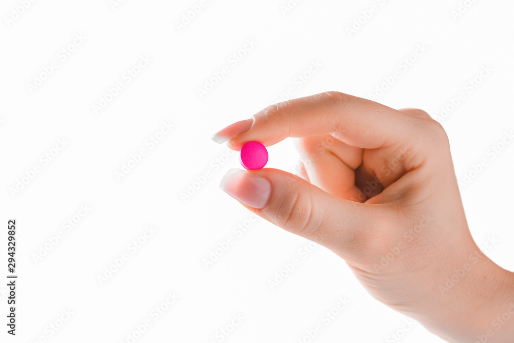 Fototapeta premium Hand holding red or pink pill on white background. Fingers holding pill close up isolated.