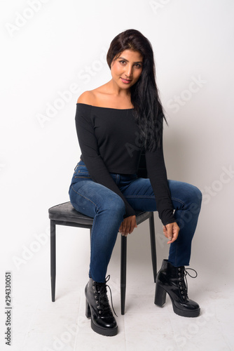 Full body shot of young beautiful Persian woman sitting on the chair