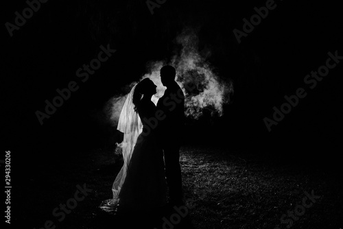 silhouette of a bride and groom at night with smoke