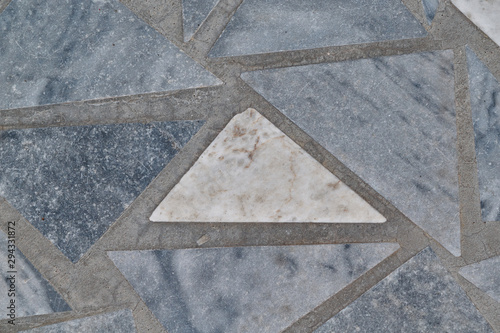 The surface of the triangular marble tiles. In the center of the white triangle, on the edges of the gray triangles. The triangles are arranged in a chaotic order. Background, texture, backdrop.