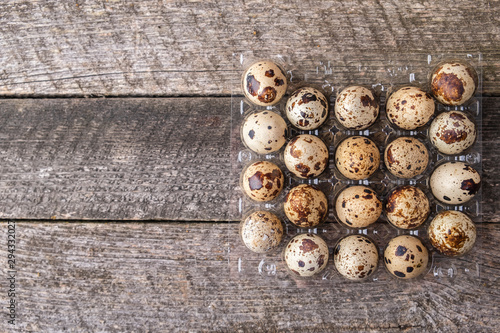 Quail eggs in packaging on a wooden background. Top view. Copy space
