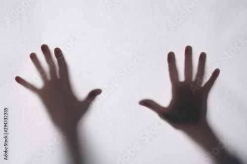 shadow or silhouette of two man's hands touching a white fabric from behind in transparncy with copy space for your text