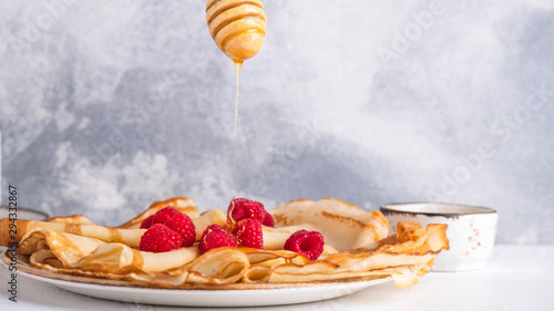 Russian pancakes with raspberries and honey. Copy space photo
