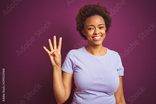 Young beautiful african american woman with afro hair over isolated purple background showing and pointing up with fingers number four while smiling confident and happy.