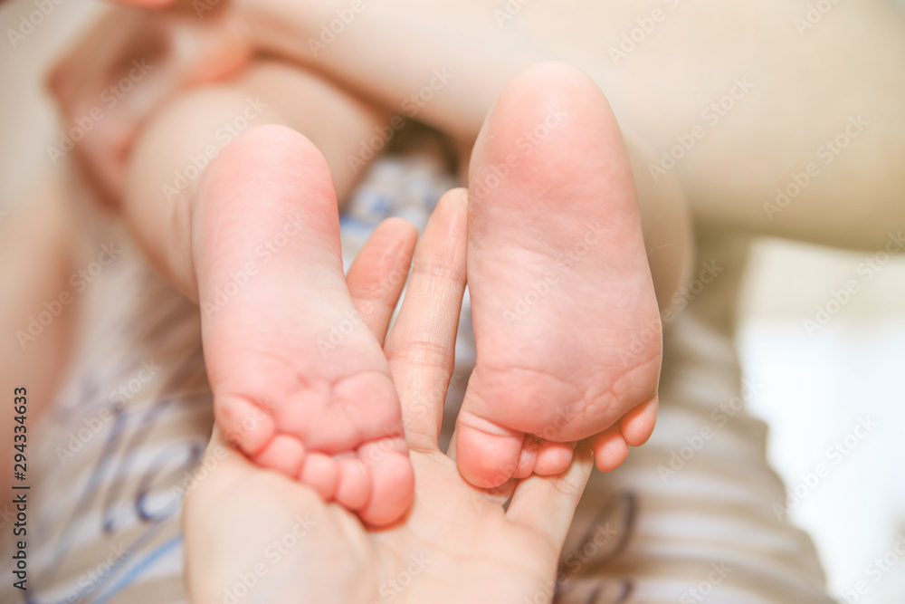 Children's legs in the caring hands of the mother. The mother and her child. The heels and toes of the baby. The concept of happy motherhood. Light gentle children's background. Children's legs in the caring hands of the mother. The mother and her child. The heels and toes of the baby. The concept of happy motherhood. Light gentle children's background.