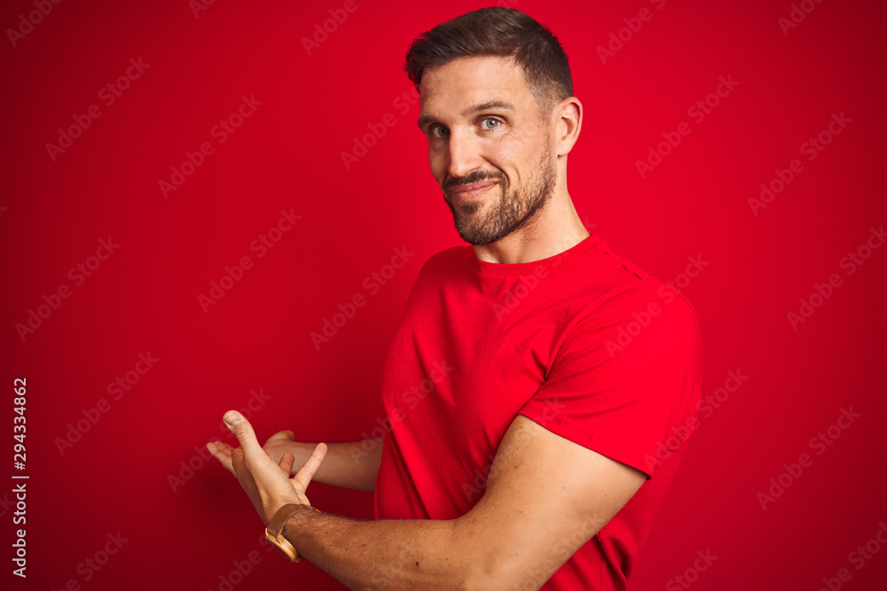 Young handsome man wearing casual t-shirt over red isolated background Inviting to enter smiling natural with open hand Young handsome man wearing casual t-shirt over red isolated background Inviting to enter smiling natural with open hand
