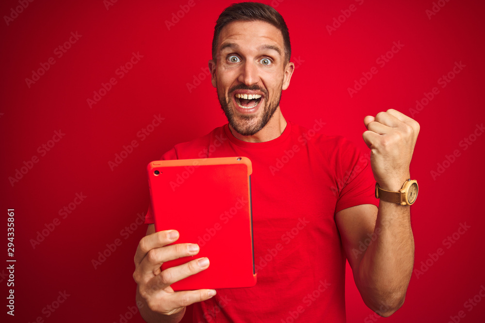 Young man using digital touchpad tablet over red isolated background screaming proud and celebrating victory and success very excited, cheering emotion Young man using digital touchpad tablet over red isolated background screaming proud and celebrating victory and success very excited, cheering emotion