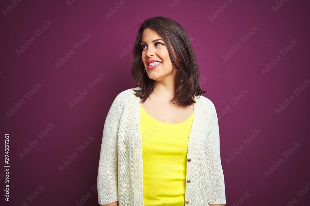 Young beautiful brunette woman a jacket over purple isolated background looking away to side with smile on face, natural expression. Laughing confident. Young beautiful brunette woman a jacket over purple isolated background looking away to side with smile on face, natural expression. Laughing confident.