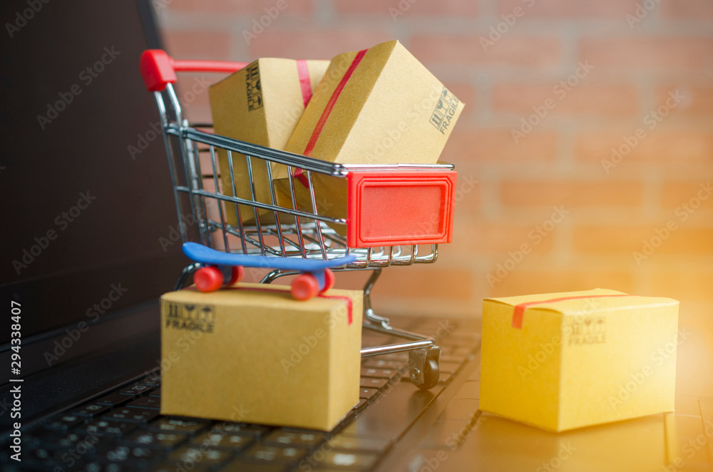 Many boxes in a trolley on a laptop keyboard,on brick background. Ideas online shopping is a form of electronic commerce that allows consumers to directly buy goods from a seller over the internet.