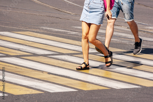 legs of young pedestrians walking on the crosswalkl