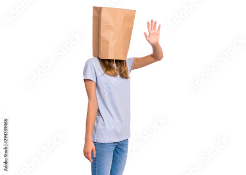 Portrait of teen girl with paper bag over head making greeting gesture with palm. Teenager cover head with bag isolated on white. Child pulling paper bag over head.