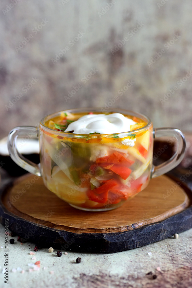 Hot soup with vegetables and meat in a beautiful transparent plate on a gray background Hot soup with vegetables and meat in a beautiful transparent plate on a gray background