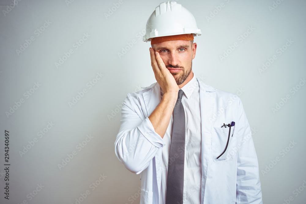 Young handsome engineer man wearing safety helmet over isolated background thinking looking tired and bored with depression problems with crossed arms.