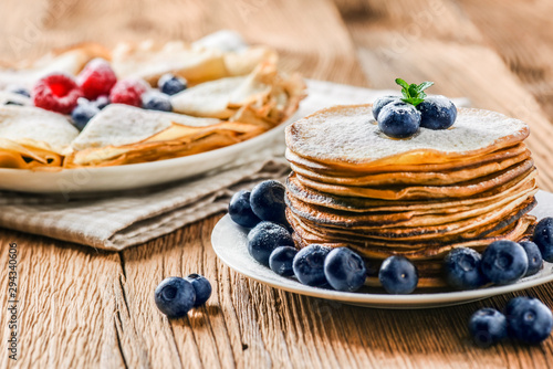 Fresh pancakes on wooden table with forest fruits like blueberries and raspberries. Pancakes with forest fruits. photo