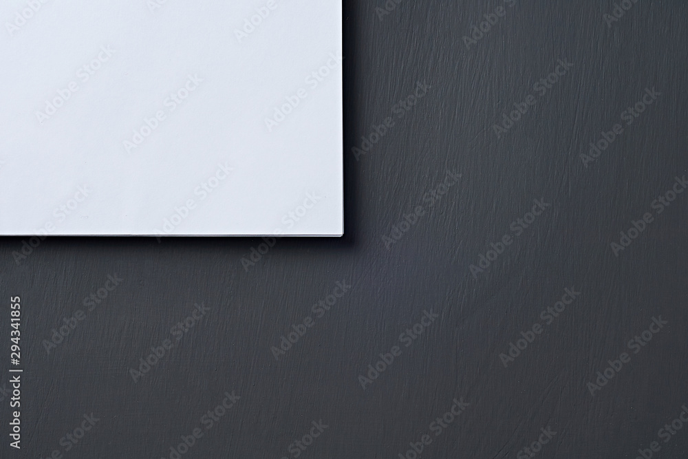Obraz premium Corner of heap of blank white paper sheets lies on dark concrete table on workplace of secretary, director, boss or other worker of company. Space for text. Top view