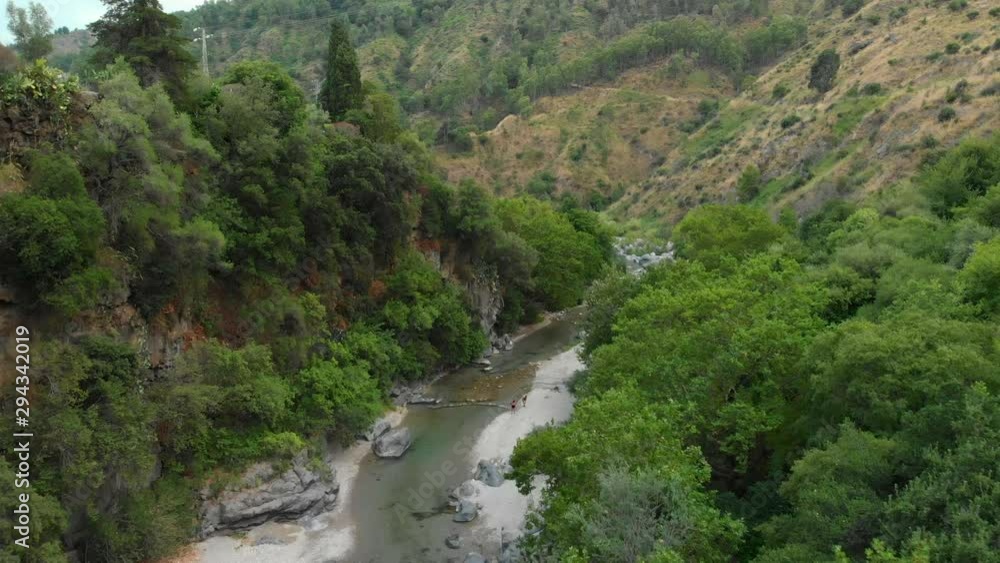 4K AERIAL DOLLY IN: Drone flying above Alcantara Gorges, an impressive channel of lava columns eroded naturally into ravines, canyons and caves. A view over the river and its crystal water and trees 4K AERIAL DOLLY IN: Drone flying above Alcantara Gorges, an impressive channel of lava columns eroded naturally into ravines, canyons and caves. A view over the river and its crystal water and trees
