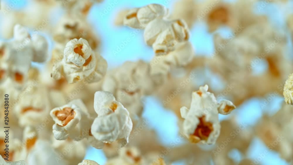 Super Slow Motion Shot of Popcorn on Blue Background after being Exploded at 1000fps. Shooted with High Speed Cinema Camera at 4K. Super Slow Motion Shot of Popcorn on Blue Background after being Exploded at 1000fps. Shooted with High Speed Cinema Camera at 4K.