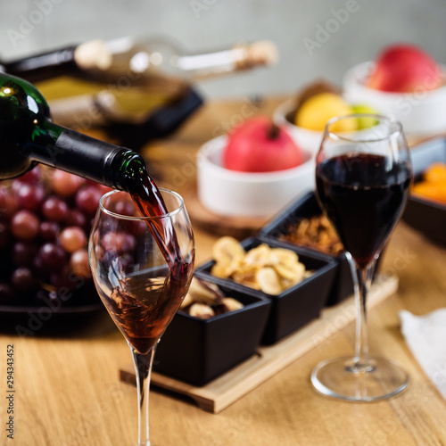 Pouring wine into glass and food background