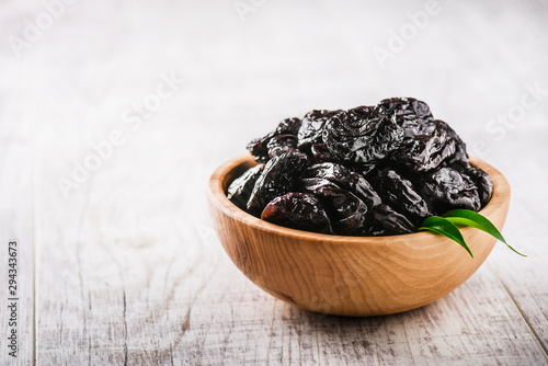 Prunes in wooden bowl on old rustic table. dried plums on table. Heap of prunes on old board.