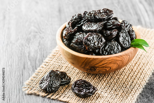 Fresh prunes in wooden bowl. Prunes on stone dark table. Prunes healthy food. Dried plums. photo