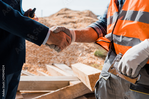 cropped view of constructor and businessman shaking hands