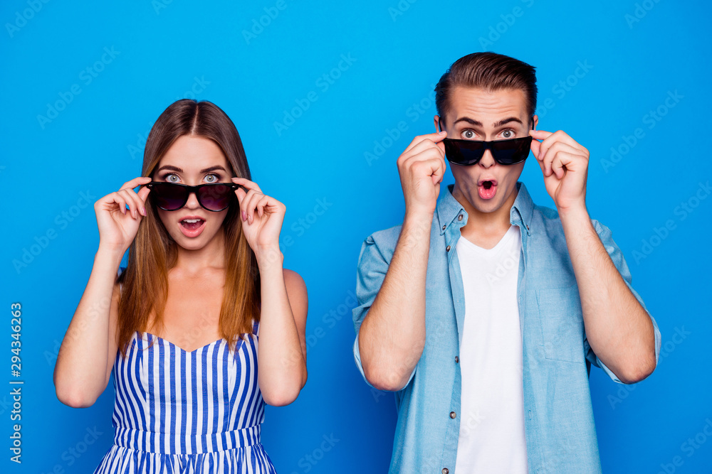Portrait of his he her she two nice attractive trendy cheerful cheery amazed impressed people touching sun specs looking at you good news isolated on bright vivid shine vibrant blue color background