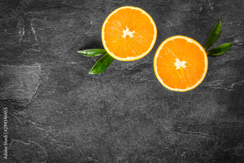 Fresh ripe tasty oranges on stone table. Orange on black background. Cut half oranges from top view. © Milan