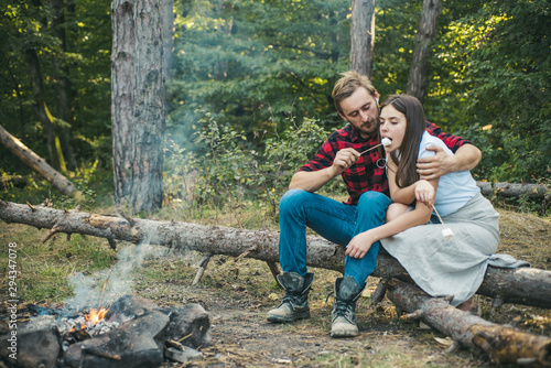 Friends enjoy weekend barbecue in forest. Happy young couple in love having picnic. Couple in love having a picnic. Find companion to travel and hike. Roasting marshmallows barbecue.