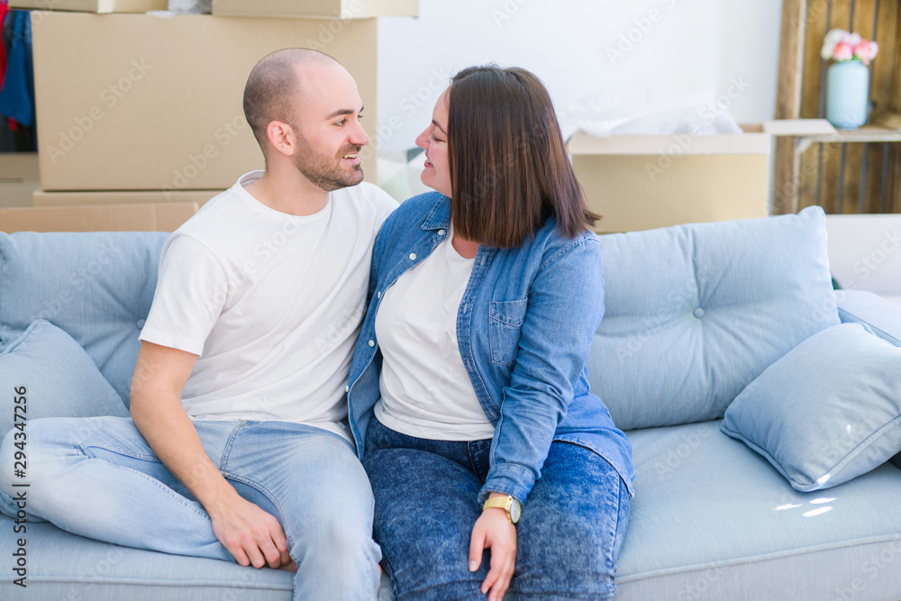 Young couple in love relaxing and hugging sitting on the sofa at new home, smiling very happy for moving to a new apartment Young couple in love relaxing and hugging sitting on the sofa at new home, smiling very happy for moving to a new apartment
