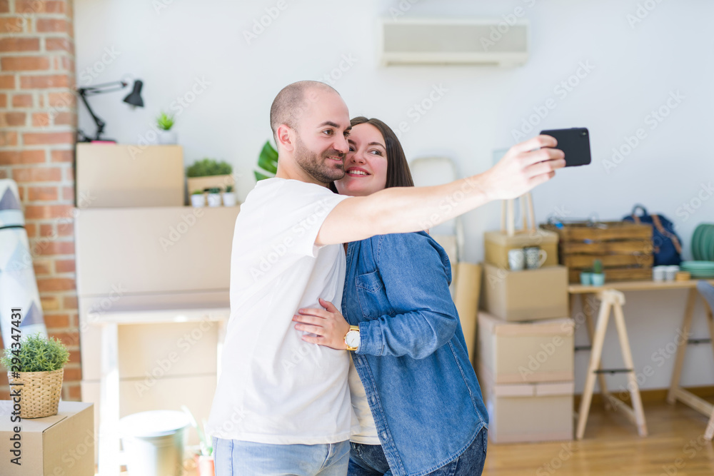 Obraz premium Young couple taking a picture photo using smartphone at new home, smiling happy for moving to new apartment