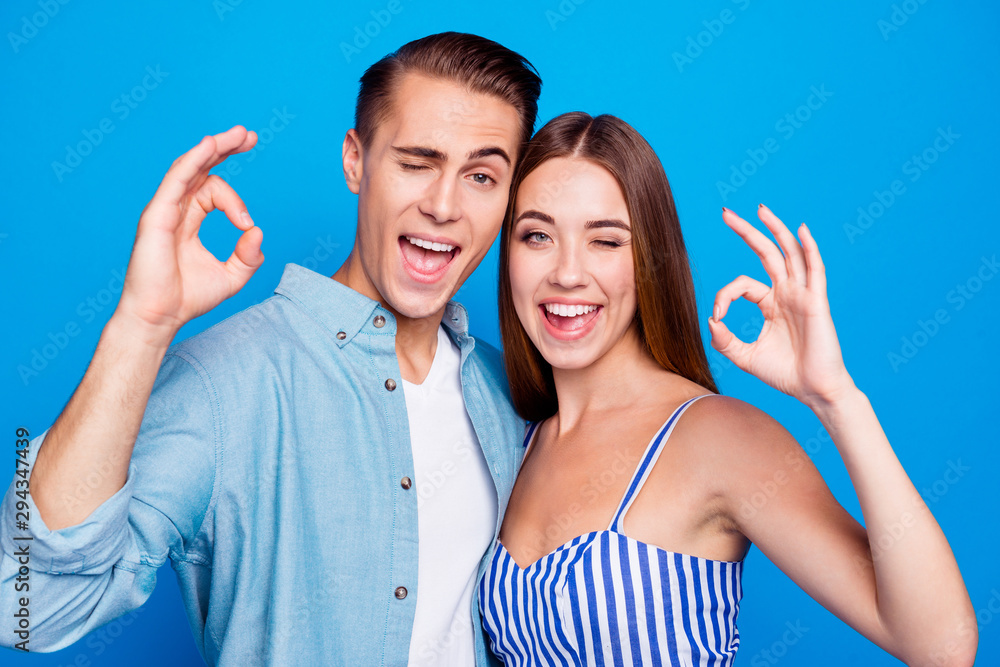 Close-up portrait of his he her she two nice attractive lovely content cheerful cheery glad people embracing showing ok-sign blinking isolated over bright vivid shine vibrant blue color background Close-up portrait of his he her she two nice attractive lovely content cheerful cheery glad people embracing showing ok-sign blinking isolated over bright vivid shine vibrant blue color background