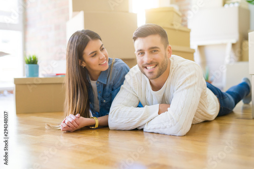 Young beautiful couple lying on the floor of new house, smiling in love very happy for moving to new apartment