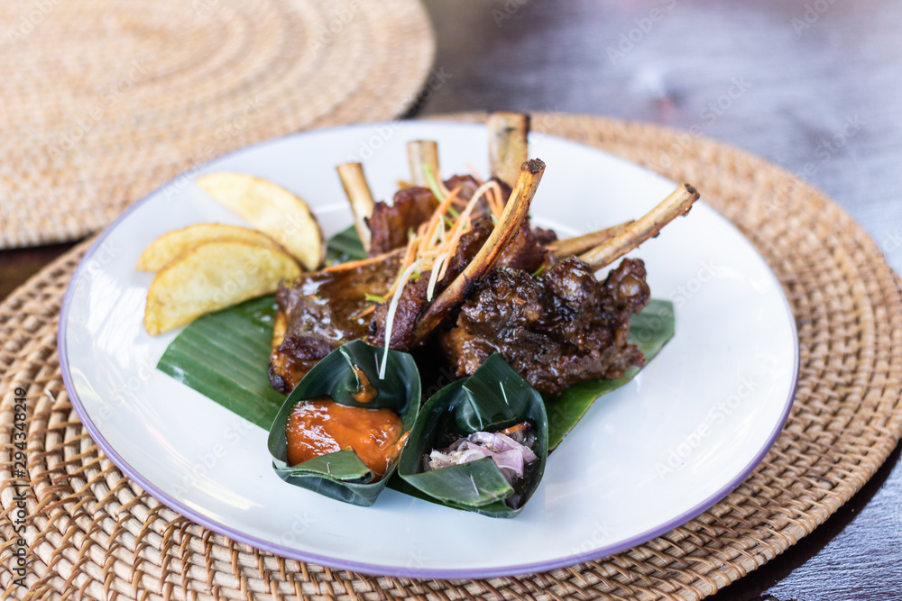 Grilled pork ribs with Indonesian style sauce on the plate. Indonesian cuisine. Grilled pork ribs with Indonesian style sauce on the plate. Indonesian cuisine.