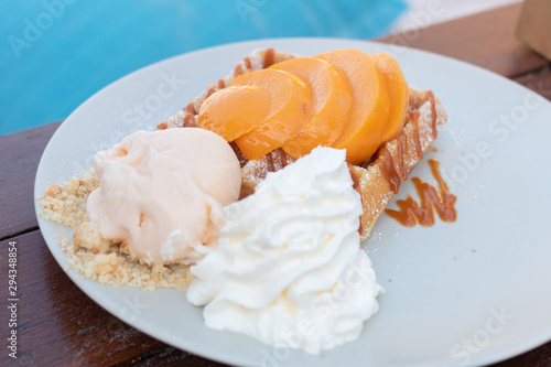 Plate of Belgian waffles with ice cream and peach